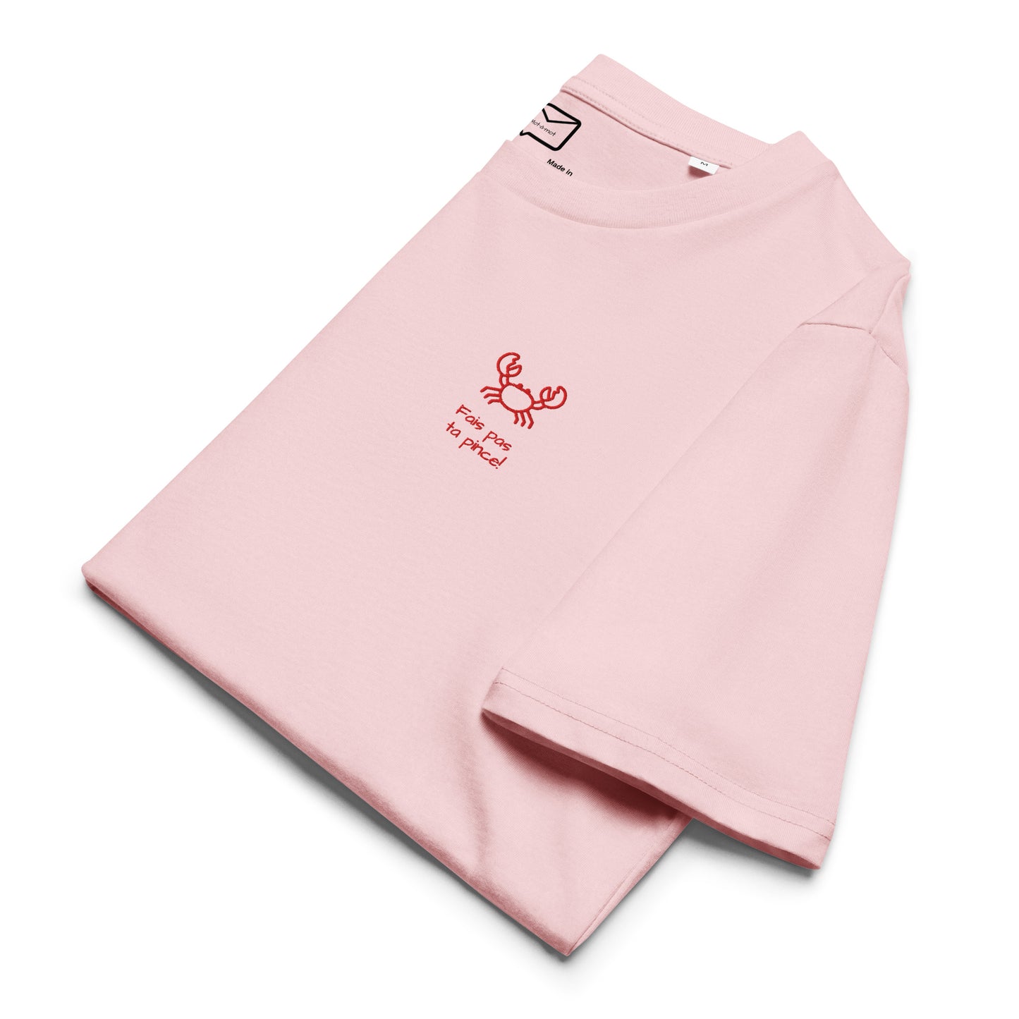 Folded view of a light pink short-sleeved t-shirt featuring a small, illustrated red crab and the humorous French phrase "Fais pas ta pince!" (Don't be stingy!) in a simple red font beneath it, located on the left side of the chest.