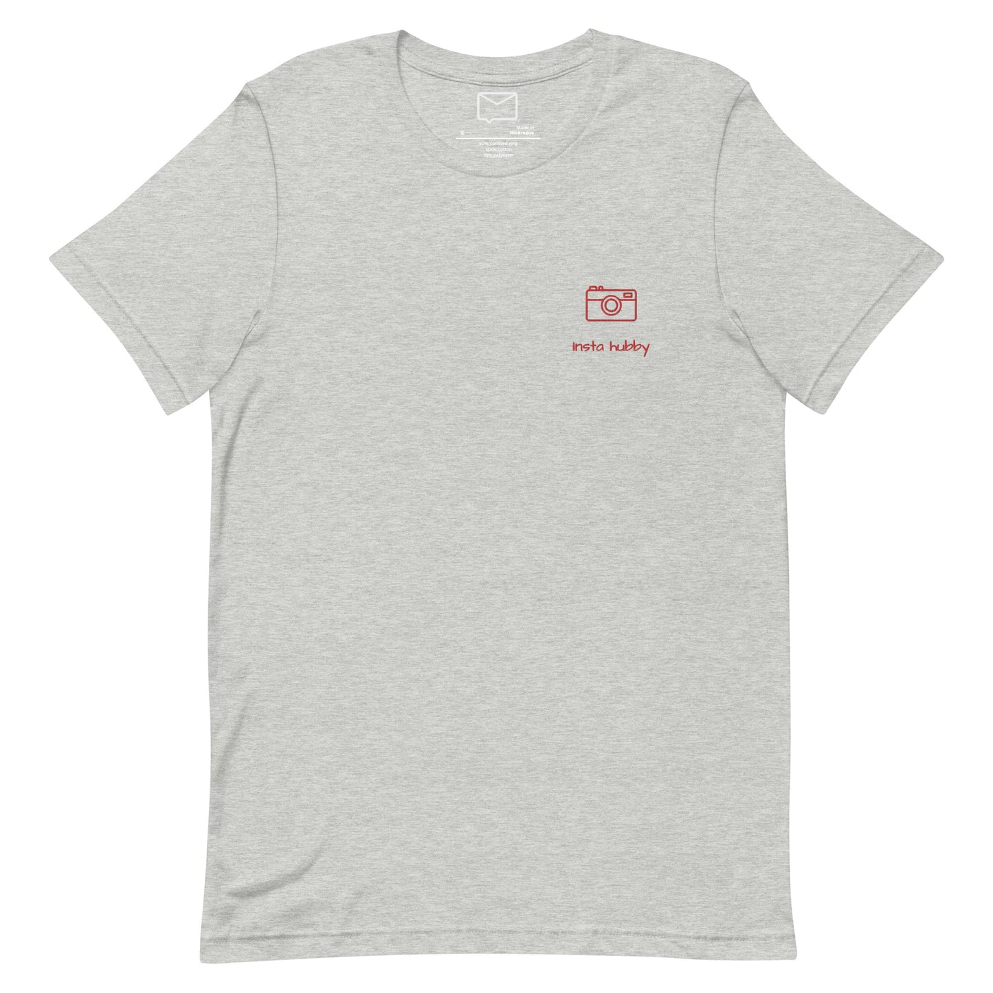 Front view of a light grey short-sleeved shirt featuring a small, red embroidered camera icon and the phrase "Insta Hubby" in a simple red font beneath it, located on the left side of the chest.