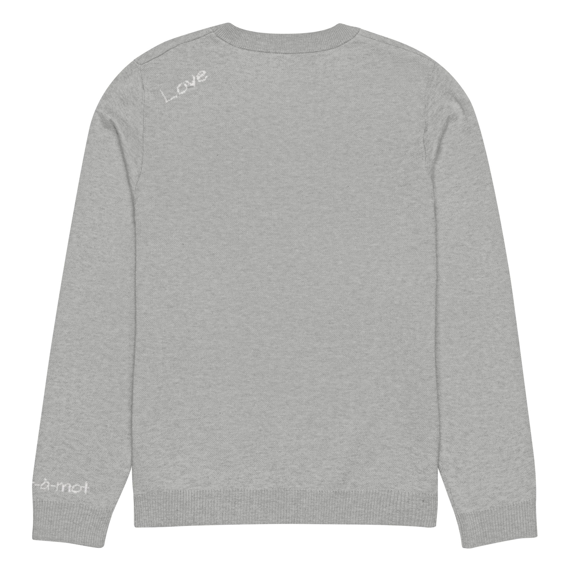 Back view of a grey knitted jumper with a ribbed neckline, cuffs, and hem. The word "Love" is written in white on the upper back. A small embroidered brand tag "mot-à-mot" is visible on the lower right sleeve