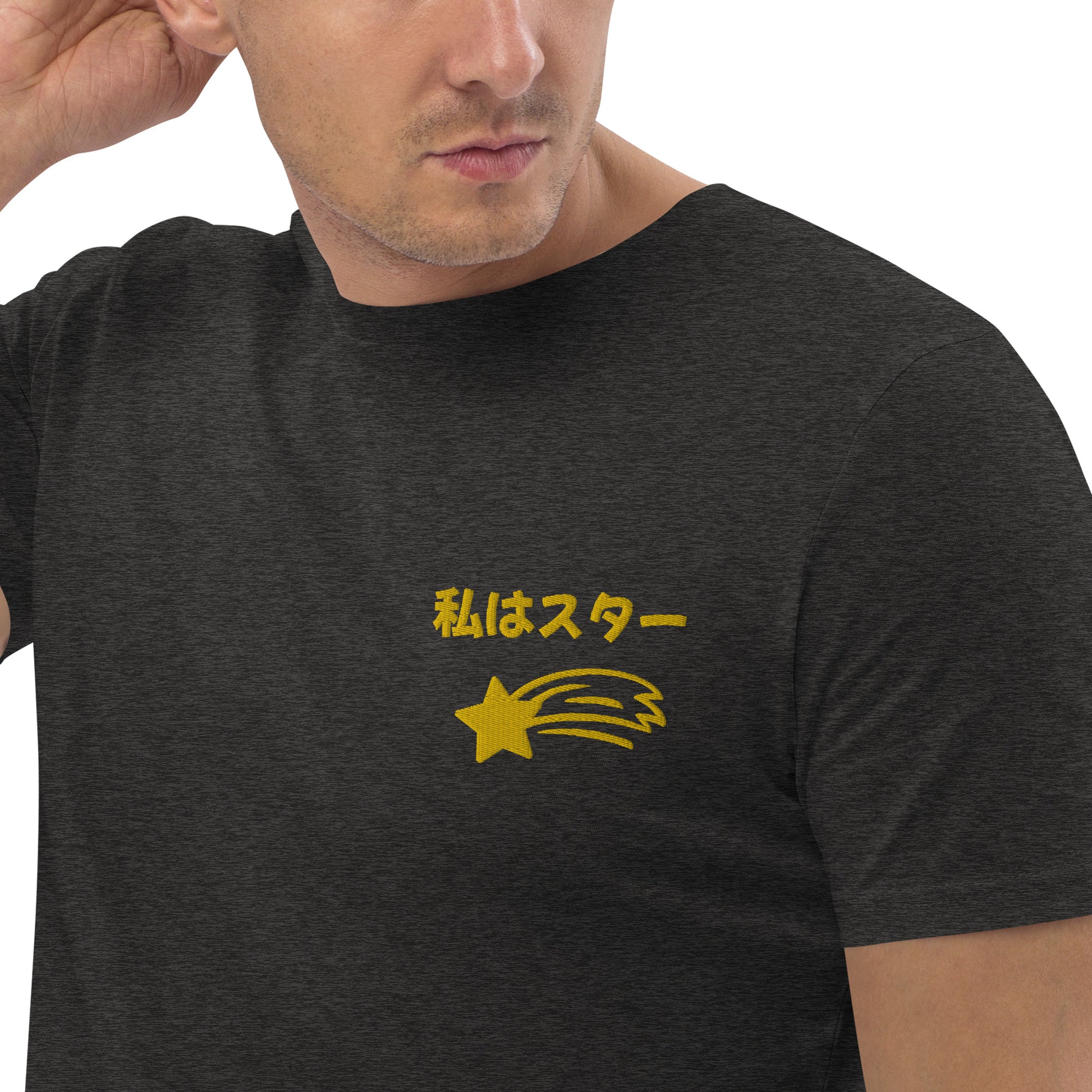 Front view of a dark short-sleeved t-shirt featuring the Japanese phrase "Watashi wa Star" (translation: I am a star) in a stylized font, accompanied by a gold shooting star graphic beneath it, located on the left side of the chest.
