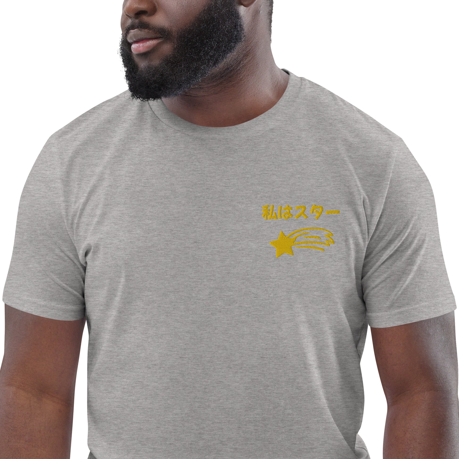 Front view of a light short-sleeved t-shirt featuring the Japanese phrase "Watashi wa Star" (translation: I am a star) in a stylized font, accompanied by a gold shooting star graphic beneath it, located on the left side of the chest.